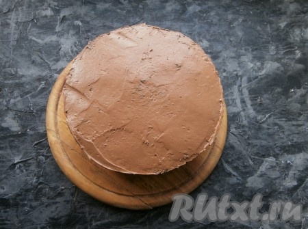 Следующим выложить более светлый корж, пропитать его немного кофейной пропиткой, смазать кремом. Последним выложить тёмный корж, пропитанный кофейной пропиткой. Верх торта и бока покрыть кремом из варёной сгущёнки и масла, выравнивая торт. Немного крема оставить для украшения.
