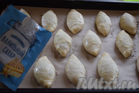 Смазываем пирожки растопленным спредом при помощи кулинарной кисти. Сверху каждый пирожок посыпаем ванильным сахаром. Так как смородина в пирожках холодная, то ставить их на расстойку не будем (ягода потечёт и даст ненужную влагу). Поэтому сразу отправляем противень с пирожками в разогретую духовку.
