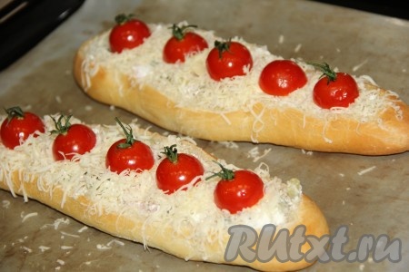 Переложить багеты на противень, застеленный пергаментом (или тефлоновым ковриком). Поверх сыра выложить половинки помидоров черри.
