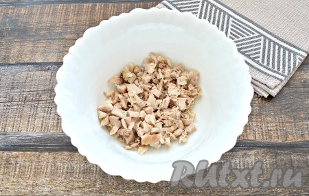 Для салата заранее отварить куриное мясо. Можно использовать филе, подойдут также голени, бёдра или куриные окорочка. Варить курятину 30 минут после закипания. Яйца отварить в течение 10 минут после закипания. Мясо и яйца остудить. 200 грамм остывшего куриного мяса нарезать на мелкие кубики и выложить в глубокую тарелку.
