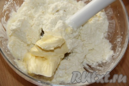 Сливочное масло предварительно достать из холодильника, чтобы оно согрелось при комнатной температуре и стало мягким. Добавить мягкое масло в миску к творожной массе.

