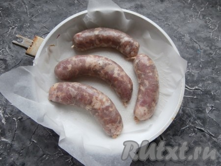 Купаты наколоть иголкой в нескольких местах, поместить в форму для запекания (или сковороду без ручки), застеленную пергаментом.
