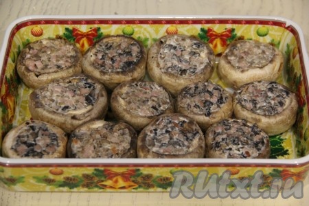 Переложить фаршированные шляпки шампиньонов в жаропрочную форму. На дно формы налить 50 мл воды.
