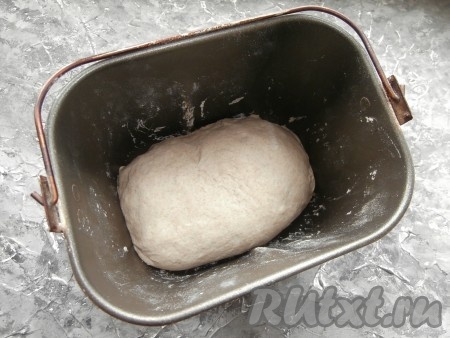 Далее тесто нужно вынуть из ведёрка и выложить на подпылённый мукой стол, растянуть его, сложить конвертом, защипнуть края и придать форму. Ведёрко почистить от приставшего теста бумажной салфеткой, убрать лопасть для замеса, чуть смазать ведёрко растительным маслом и поместить в него тесто защипами вниз.
