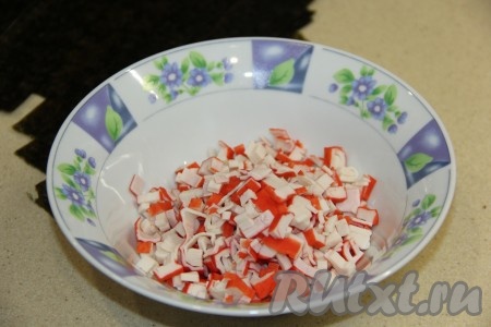 Крабовые палочки разморозить при комнатной температуре, а затем мелко нарезать.
