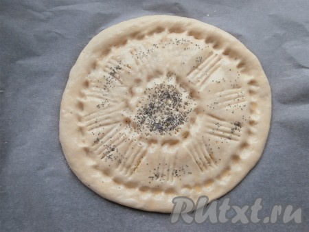 Комок теста с картофелем перевернуть и аккуратно придавить руками, придавая форму лепёшки толщиной около 0,7-1 см. Смазать каждую лепёшку желтком, чуть взбитым с молоком, посыпать сверху маком. Можно вилкой (или пальцами) нанести на поверхности каждой лепёшки какой-либо рисунок. У нас получатся 2 лепёшки с картофельной начинкой. Лепёшку выложить на лист пергамента.
