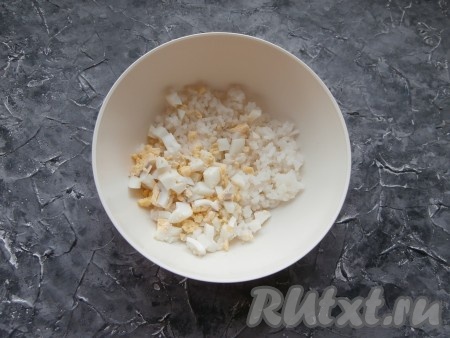 Яйца сварить заранее (варить после закипания воды минут 8-10), затем переложить в холодную воду, чтобы яйца остыли, а после этого очистить. В глубокую миску выложить варёный рис, добавить рубленные варёные яйца.
