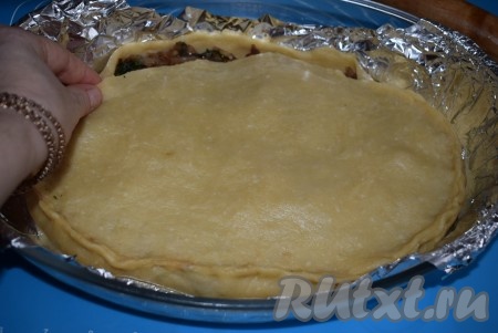 Далее, также при помощи скалки, переносим меньшую раскатанную часть теста, накрывая ею начинку. Пальцами скрепляем обе части теста, формируя закрытый пирог.
