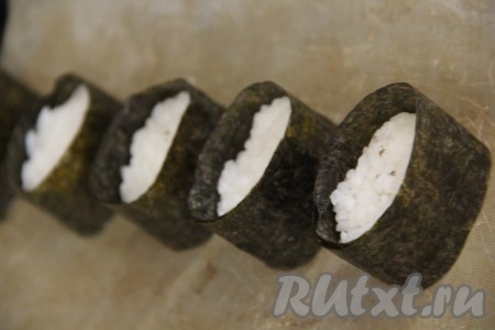 Обернуть каждый комочек риса подготовленной полоской из листа нори, край полоски нори слегка смочить и приклеить к другому краю листа. У нас должны получиться вот такие заготовки (как на фото) - лодочки с бортиком. Переложить заготовки на противень, застеленный пергаментом.
