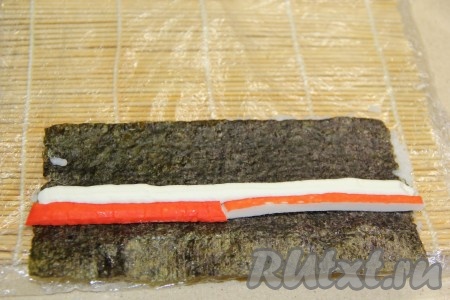 Выдавить возле крабовых палочек полоску творожного сыра.
