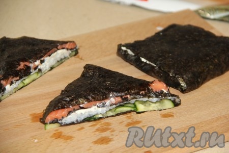 Затем завершить квадрат слоем с творожным сыром. Он хорошо скрепит все квадраты нашего ленивого ролла. Острым ножом разрезать квадрат на две части по диагонали и у нас получатся 2 треугольника - это и будут 2 ленивых ролла. Таким образом сформировать оставшиеся роллы.
