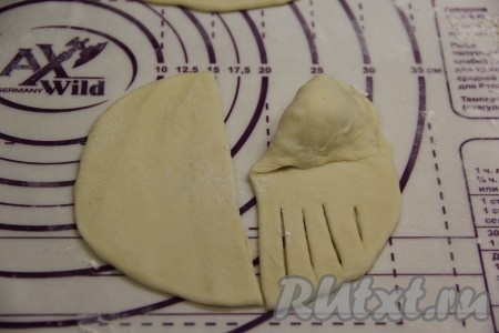 Начиная с края с начинкой, свернуть тесто в виде треугольника, формируя пирожок с творогом и изюмом.
