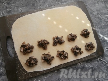 Тесто нужно очень тонко раскатать (чем тоньше, тем лучше) на припылённой мукой поверхности. Визуально (или намечая тыльной стороной лезвия ножа) разделить тесто на квадраты размером 5 см х 5 см на одной половине теста (как на фото). В центр каждого квадрата выложить по 1-2 чайные ложки грибной начинки.
