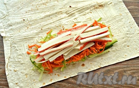 Крабовые палочки очистить от слюды, нарезать средней соломкой и выложить на морковь.