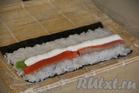 Рядом с рыбой и авокадо выдавить полоску творожного сыра. Я выкладываю сыр в кулинарный мешок, так удобнее его наносить ровной полоской на рис.