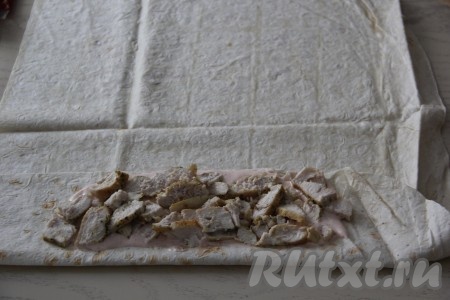 Каждый лаваш разрезать на 2 части. Из указанного количества ингредиентов мы будем готовить 4 шавермы с курицей в лаваше, поэтому курицу, капустный салат, помидоры, огурцы и сыр надо будет разделить на 4 части (по количеству шаверм). Пожаренное филе курицы нарезать на кусочки. Один край лаваша загнуть, примерно, на 10 сантиметров. Эти 10 см смазать частью соуса и выложить 1/4 часть нарезанной курицы по центру загнутого лаваша, оставив по краям по 4-5 см без начинки (как на фото).