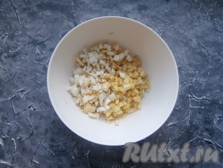 Предварительно нужно отварить в кипящей воде яйца в течение 8-10 минут и картофель в кожуре в течение 30-40 минут (готовые картошины будут легко прокалываться ножом), остудить и очистить. Картофель и яйца нарезать небольшими кубиками, выложить в достаточно объёмную миску.