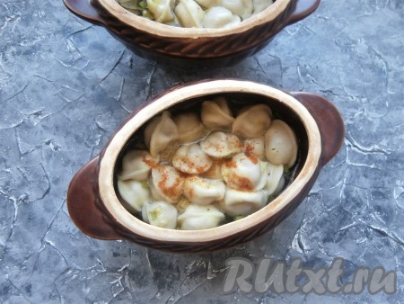 Накрыть горшочки крышками и отправить их в разогретую до 180 градусов духовку на 25 минут. Полностью готовые пельмени перемешать с бульоном и посыпать красным молотым перцем.