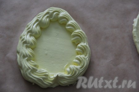 Оставшуюся часть белков выложить в кулинарный мешок с фигурной насадкой. По краю каждого пасхального яйца отсадить белки в виде рифлёной волны (как на фото).