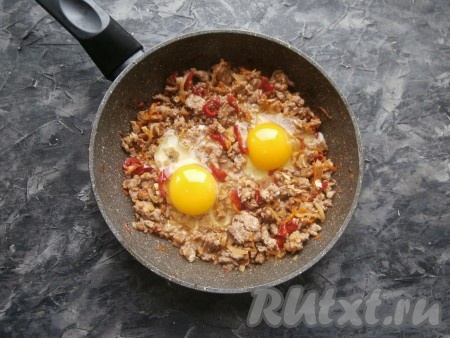 Прямо в фарш, сделав вилкой небольшие луночки, вбить сырые яйца. Чуть посолить яйца и, накрыв сковороду крышкой, на небольшом огне готовить яичницу с фаршем 4-5 минут (до тех пор, пока не свернётся белок).