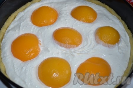 На тесто равномерно распределяем получившуюся творожную начинку. Раскладываем половинки консервированных персиков, немного утапливая их в творожную массу.