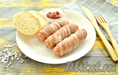 Аппетитное, вкусное, сытное блюдо из сосисок и бекона готово, достаём его из духовки и подаём к столу в горячем виде, дополнив ломтиками хлеба и любимым соусом.