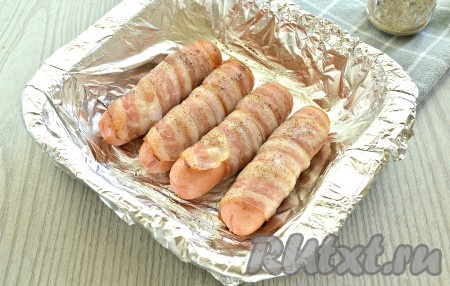 Форму с сосисками в беконе поставить в разогретую духовку и запекать 10-15 минут при температуре 190 градусов. Продолжительность запекания во многом зависит от свойств духовки.