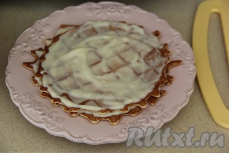 Для формирования вафельного торта выложить одну вафлю на плоскую тарелку, смазать заварным кремом, сверху выложить следующую вафлю и тоже смазать кремом.