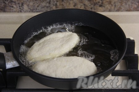В сковороду влить достаточно много масла и очень хорошо его разогреть, в получившийся фритюр аккуратно опустить пирожки швом вниз. Масла должно быть столько, чтобы оно доходило до середины пирожков.