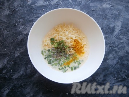К смеси молока и яиц добавить нарезанный зелёный лук, чёрный молотый перец и куркуму, выложить натёртый на крупной тёрке сыр, хорошенько перемешать яично-сырную смесь.