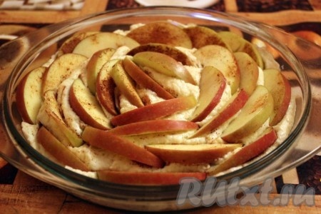 Форму для выпечки смазать растительным маслом. Выложить в подготовленную форму тесто. Сверху разместить нарезанные кусочки яблок, утопив их основательно в тесто. У меня была круглая стеклянная форма, я разместила яблоки по кругу.