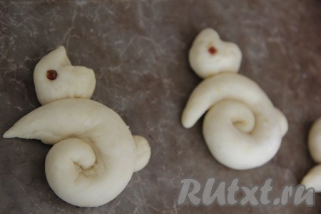 Оставить "зайчиков" на 30 минут в тёплом месте. Затем из изюма (или чернослива) вырезать маленькие кружочки - это будут глазки зайчиков и аккуратно вставить, слегка вдавив в тесто. 