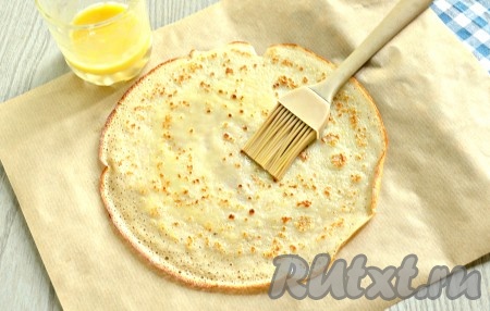 Блины готовы. Начинаем сборку пиццы из блинов. Кстати, сразу включайте духовку, выставив температурный режим на 180 градусов. В небольшой мисочке необходимо смешать майонез и кетчуп. Отрезать кусок пергамента. Выложить на него 1 блин, смазать его взбитым желтком (мы оставляли его вначале, перед приготовлением блинного теста).