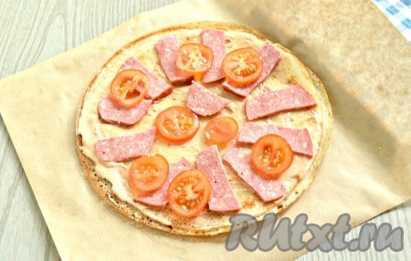 Нарезать колбасу тонкими брусочками, помидоры черри - колечками. Выложить помидоры и колбасу на блинную основу.