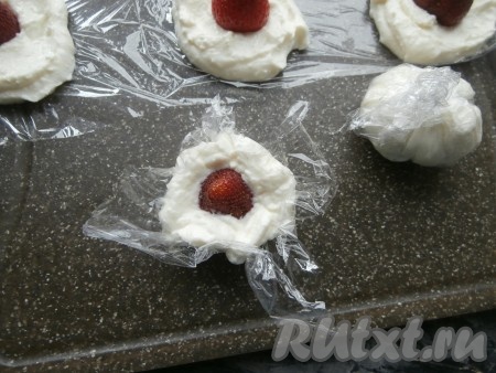 Далее каждую лепёшку аккуратно, подгибая кверху края плёнки, свернуть в шарик так, чтобы клубника была внутри творога.