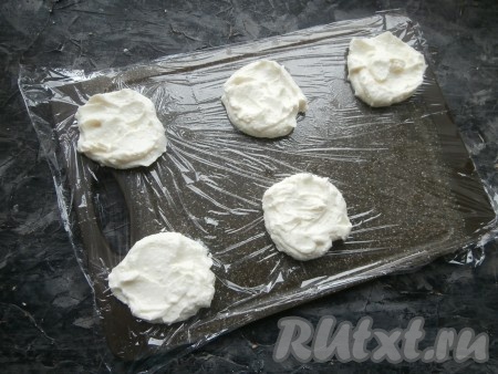 На столе (или доске) расстелить пищевую плёнку, разрезать её на 5 больших квадратов (по количеству пирожных). Творожную массу разделить на 5 частей и выложить ложкой в каждый квадрат.