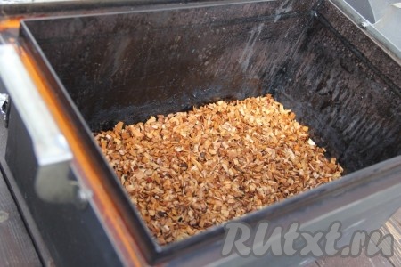 Подготовить коптильню: заранее замочить щепу в воде на 15-20 минут. Я наливаю воду в пакет с щепой ольхи и оставляю на 15-20 минут, а затем делаю несколько проколов в пакете и лишняя вода стекает. На дно коптильни выложить подготовленную щепу и равномерно распределить её.