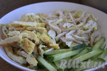 В глубокой миске соединить нарезанные огурцы, куриное филе и яичный блинчик, добавить заправку, перемешать и дать салату настояться минут 20 в холодильнике.