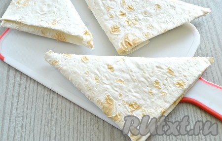 Свернуть так всю полоску лаваша, формируя треугольник. Получаются вот такие треугольные заготовки пирожков с капустой.
