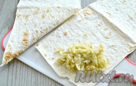 На край каждой полоски из лаваша выложить по 2 столовые ложки капустой начинки. Подвернуть край полоски в форме треугольника.