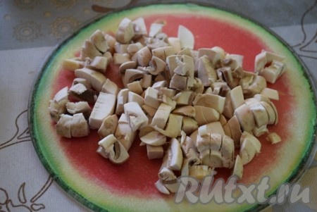 Шампиньоны очищаем от кожицы (вместо шампиньонов можно взять и предварительно отваренные в течение 25-30 минут лесные грибы) и нарезаем на мелкие кубики.