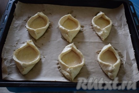 Сформированные лодочки аккуратно перекладываем на противень, застеленный пергаментом. Лодочки выкладываем на расстоянии друг от друга. Смазываем поверхность лодочек сырым яйцом, предварительно взбитым до однородности с помощью вилки.