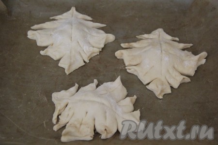 Переложить заготовки слоёных пирожков с яблоками на противень, застеленный пергаментом. Чтобы наши пирожки ещё больше напоминали листочки, сделать желобки на каждом пирожке по центру и по бокам при с помощи пластикового ножа (или обратной стороной чайной ложки).