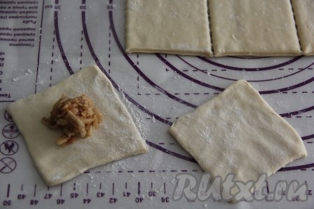 Каждый квадратик размять пальцами, чтобы тесто стало тоньше. На один подготовленный квадратик теста выложить, примерно, 1 чайную ложку яблочной начинки.