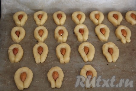 Выложить печенье с миндалём на противень, застеленный пергаментом. Желательно выкладывать заготовки не слишком близко друг к другу.