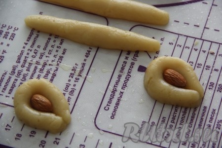 Из каждой колбаски сформировать подковку, в середину выложить миндаль (как на фото).