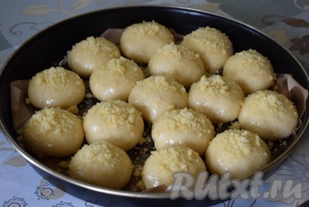 Подошедшие булочки смазываем взбитым вилкой яйцом и сверху посыпаем охлаждённым штрейзелем.