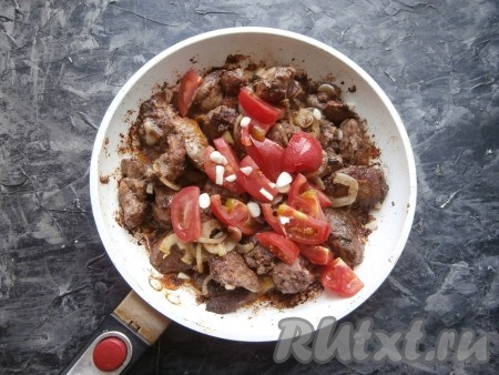 Обжаривать куриную печень с луком и перцем минуты 3-4, иногда переворачивая, затем добавить свежие помидоры, нарезанные дольками (по желанию с помидоров можно предварительно снять кожуру), и чеснок, нарезанный на кусочки.