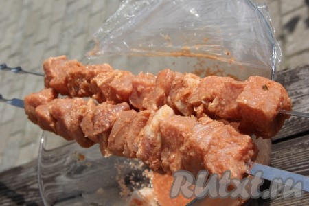 Нанизать кусочки замаринованной свинины на шампуры.