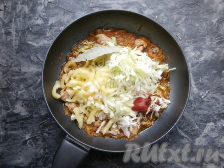 По прошествии времени добавить к мясу нашинкованную капусту, томатную пасту, нарезанный соломкой болгарский перец (по желанию), измельчённый чеснок и лавровый лист, перемешать, протушить на небольшом огне 10-15 минут (до мягкости капусты).